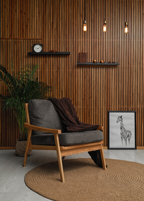 Akustikwandverkleidung aus Holzlammellen auf Filz von Tischlerei erstellt, mit Stuhl und Zimmerpflanzen für ästhetischen Innenausbau.